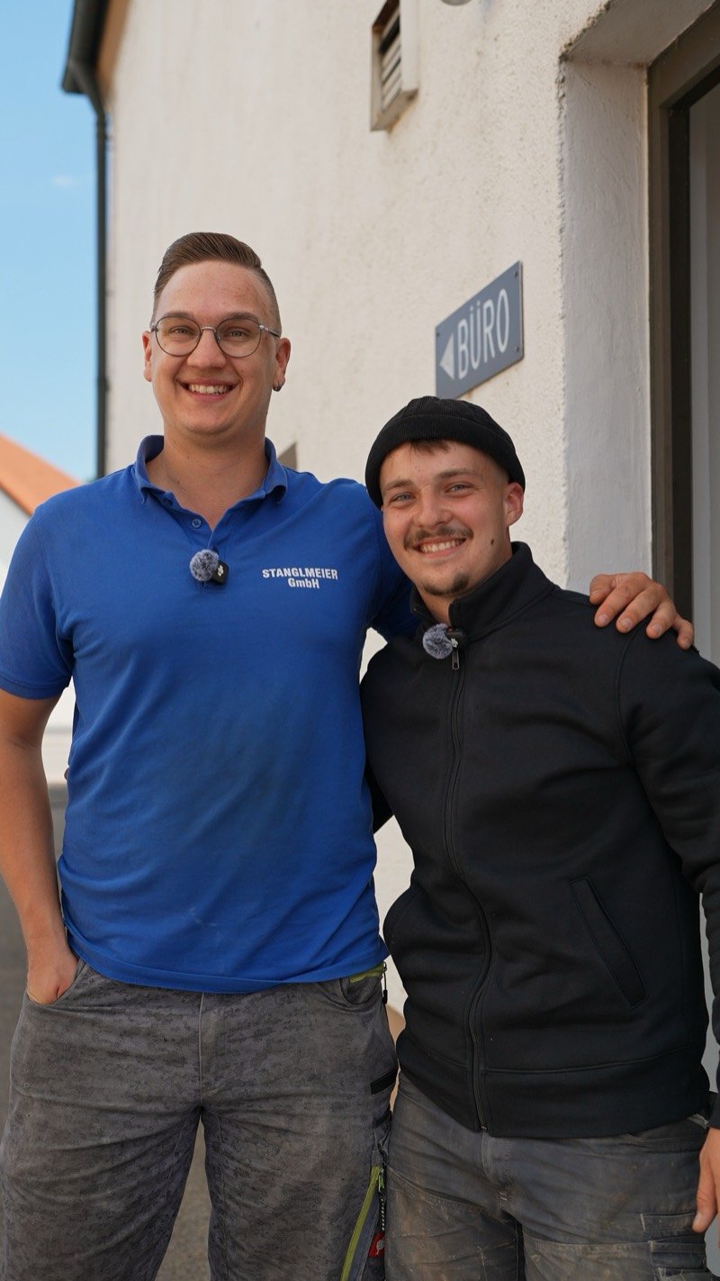Zwei Kollegen Arm in Arm vor dem Büroeingang in Altdorf